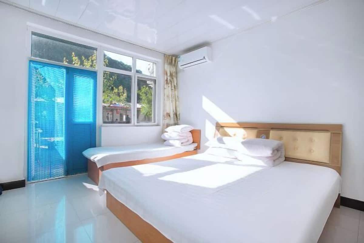 A hotel room with a bed, a window, and an air conditioning unit.