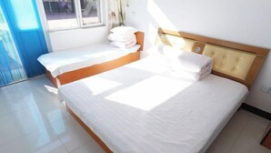 A bedroom with a large bed, a wooden headboard, and a window providing natural light.
