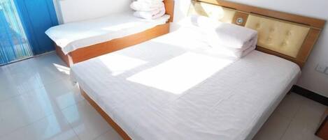 Une chambre dotée d’un grand lit, d’une tête de lit en bois et d’une fenêtre laissant entrer la lumière naturelle.