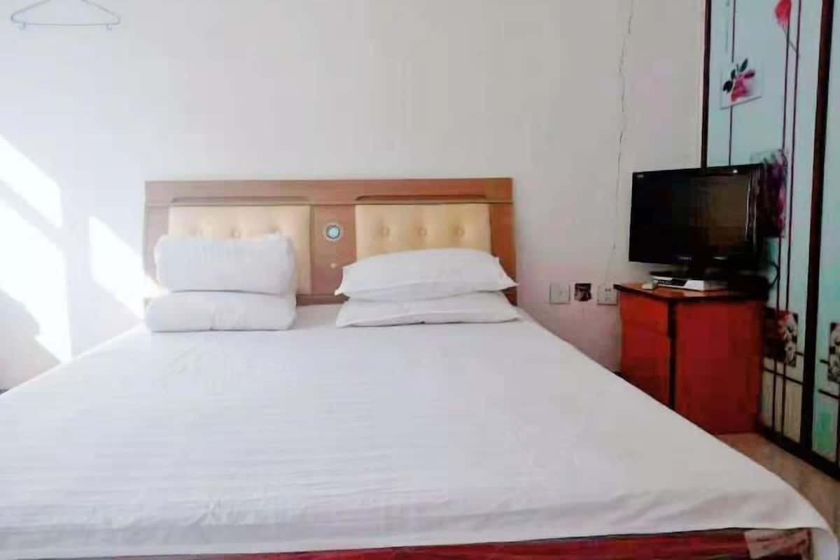 A single bed with a wooden headboard, a television on a stand, and a red cabinet.