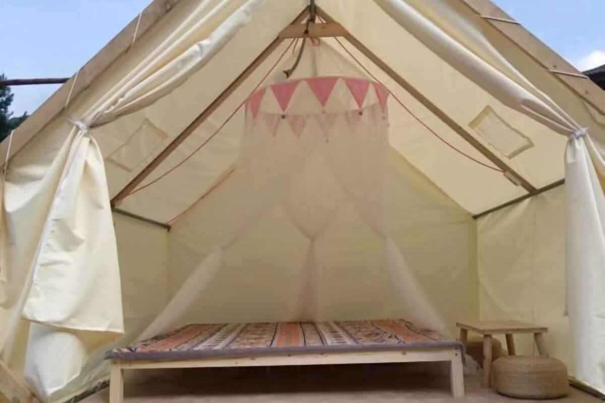A tent with a bed, a small table, and a hanging canopy.