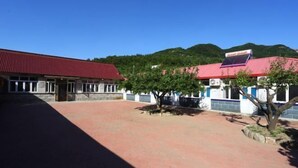 A building with a red roof, a paved courtyard, and a solar panel on the roof.