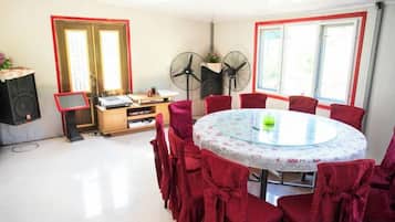 A dining area with a round table, red chairs, and a piano.