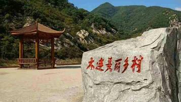 A rock with carved text, a pavilion, and a mountainous backdrop.