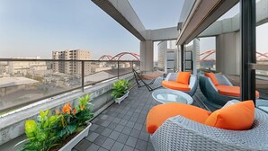 Terraço no telhado com área de estar ao ar livre, plantas em vasos e vista da cidade.