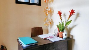 Un comptoir d’accueil avec un classeur bleu, des papiers, une plante en pot et une tasse.
