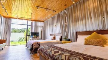 Une chambre d’hôtel avec un plafond en bois, deux lits, une télévision et une vue sur la verdure.