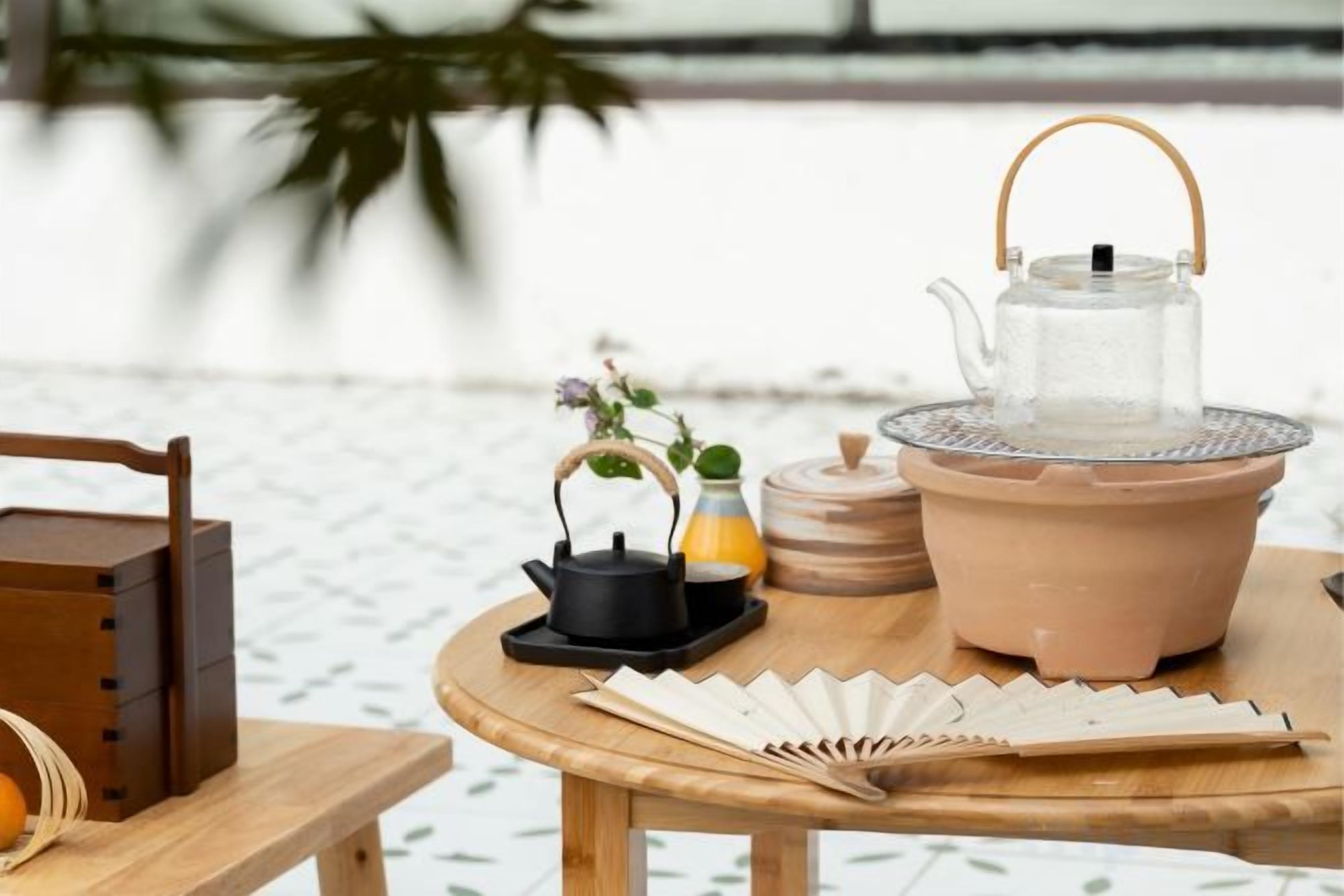 Una mesa con un calentador de agua, una tetera y una taza de té.