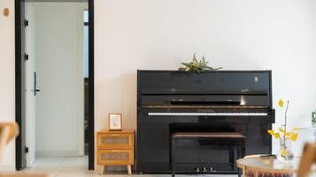 Una habitación con un piano, un pequeño aparador de madera y una puerta.