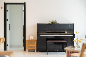 Una habitación con un piano, un pequeño aparador de madera y una puerta.