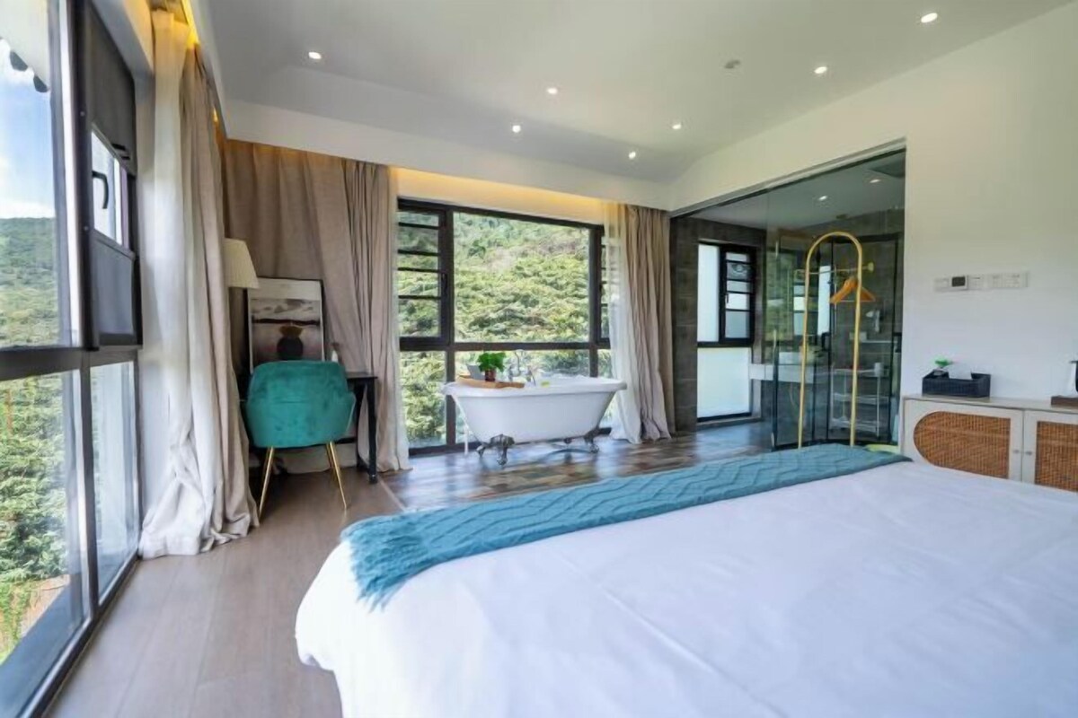 Un dormitorio moderno con una cama grande, una bañera y una zona de ducha con mampara de vidrio.