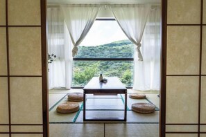 A traditional Japanese room with tatami flooring, a low table, and a view of a lush green landscape. - Carefree Valleys (Suzhou Qiyuan Road Store) (Suzhou)