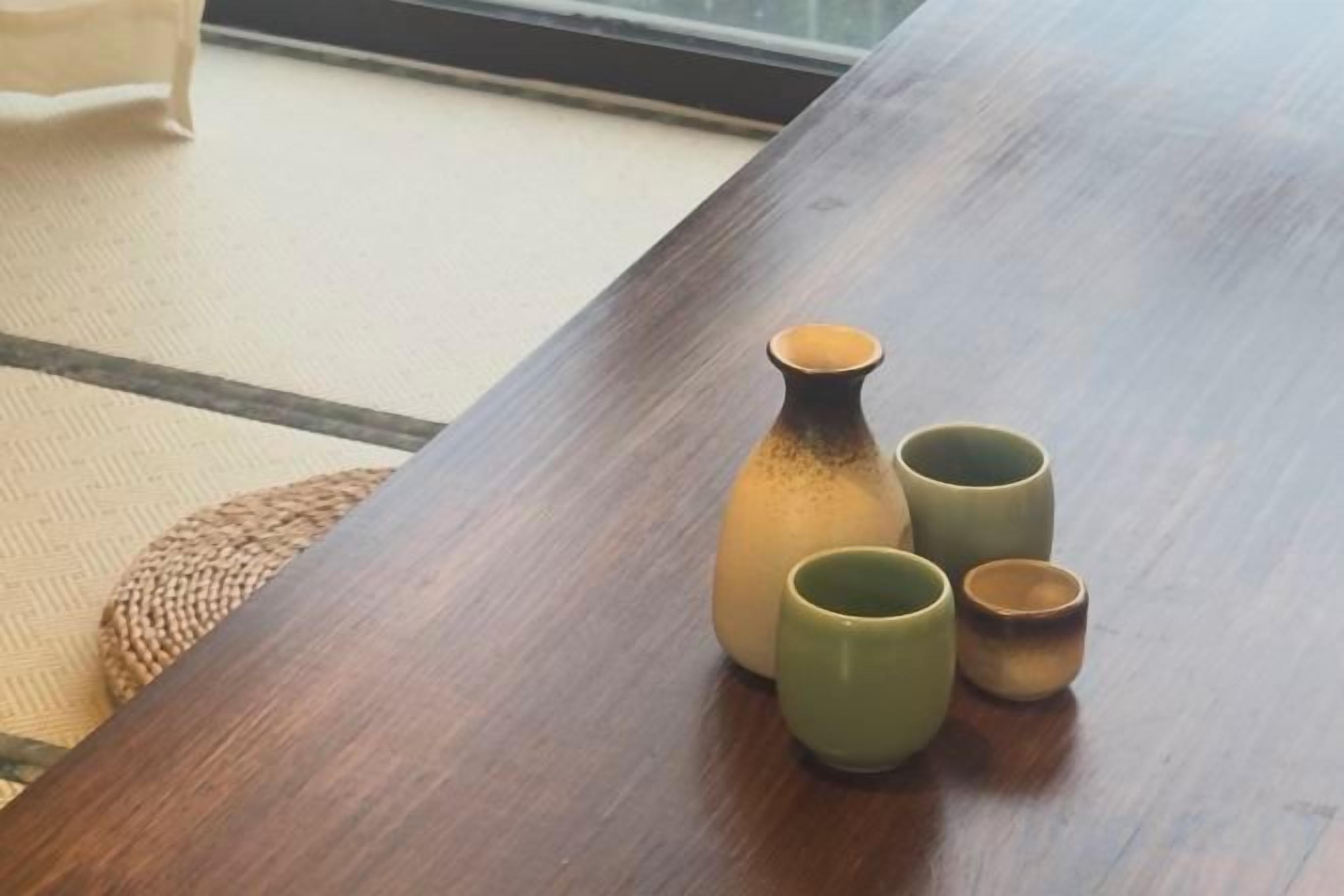 Una mesa de madera con un florero y dos tazas.