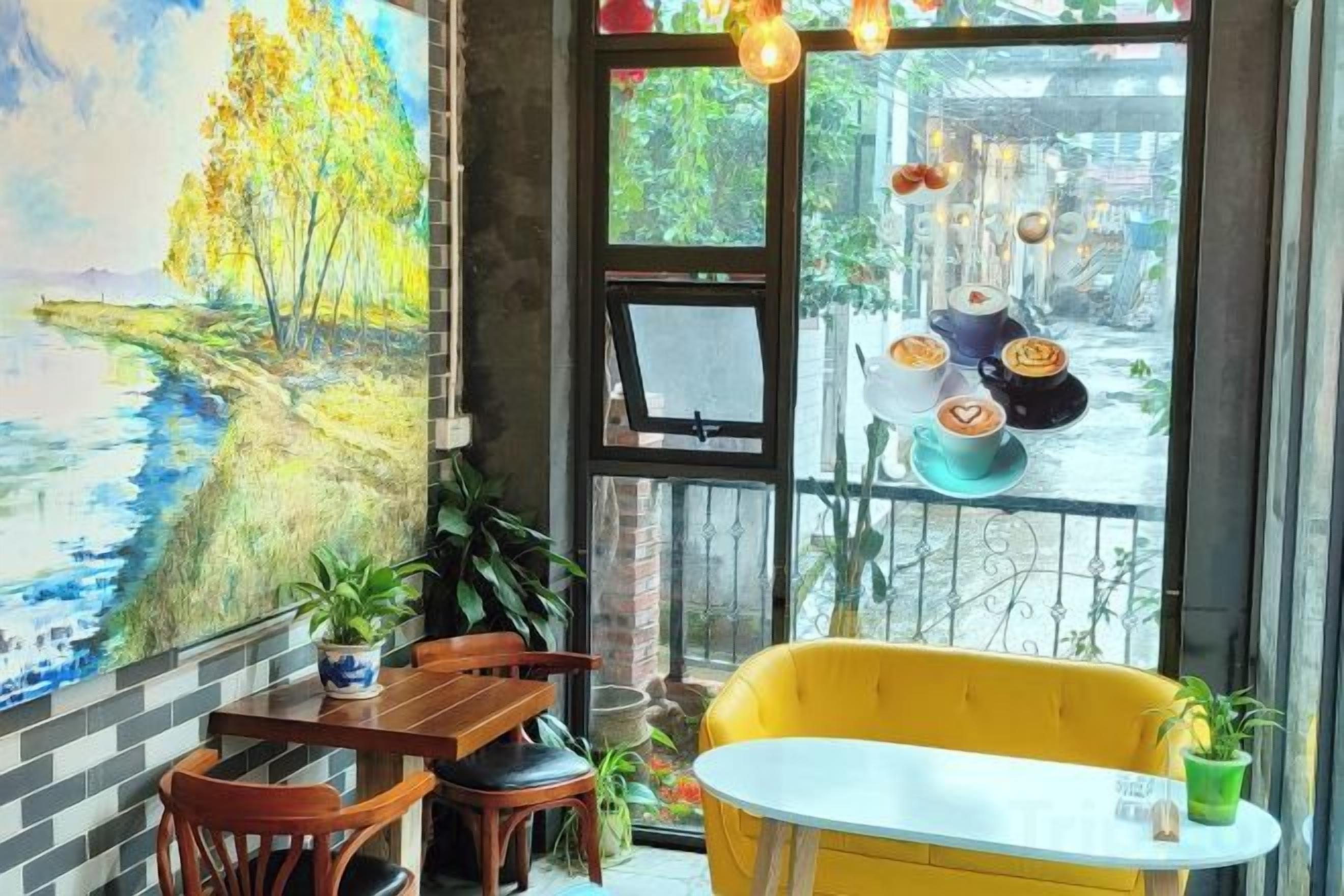 A dining area with a table and chairs, a yellow sofa, and a large window with a view of the street.