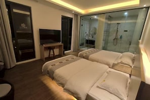 Ein Hotelzimmer mit zwei Betten, einem Fernseher, einem Schreibtisch und einer Duschkabine.