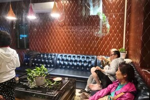 A room with a blue leather sofa, a potted plant, and a table with a decorative item.