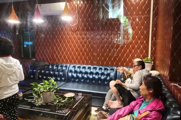 Ein Zimmer mit einem blauen Ledersofa, einer Topfpflanze und einem Tisch mit einem dekorativen Gegenstand.