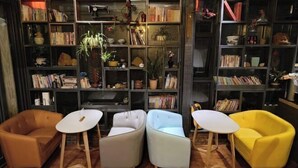 Un coin lecture accueillant, avec quatre fauteuils et deux petites tables, entouré d’étagères hautes remplies de livres et d’objets décoratifs.