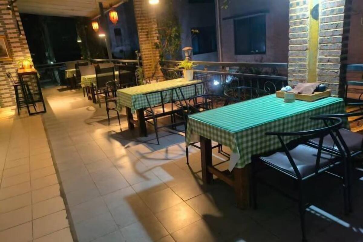 Un espace de restauration en plein air avec des tables et des chaises, un mur en briques et un balcon.