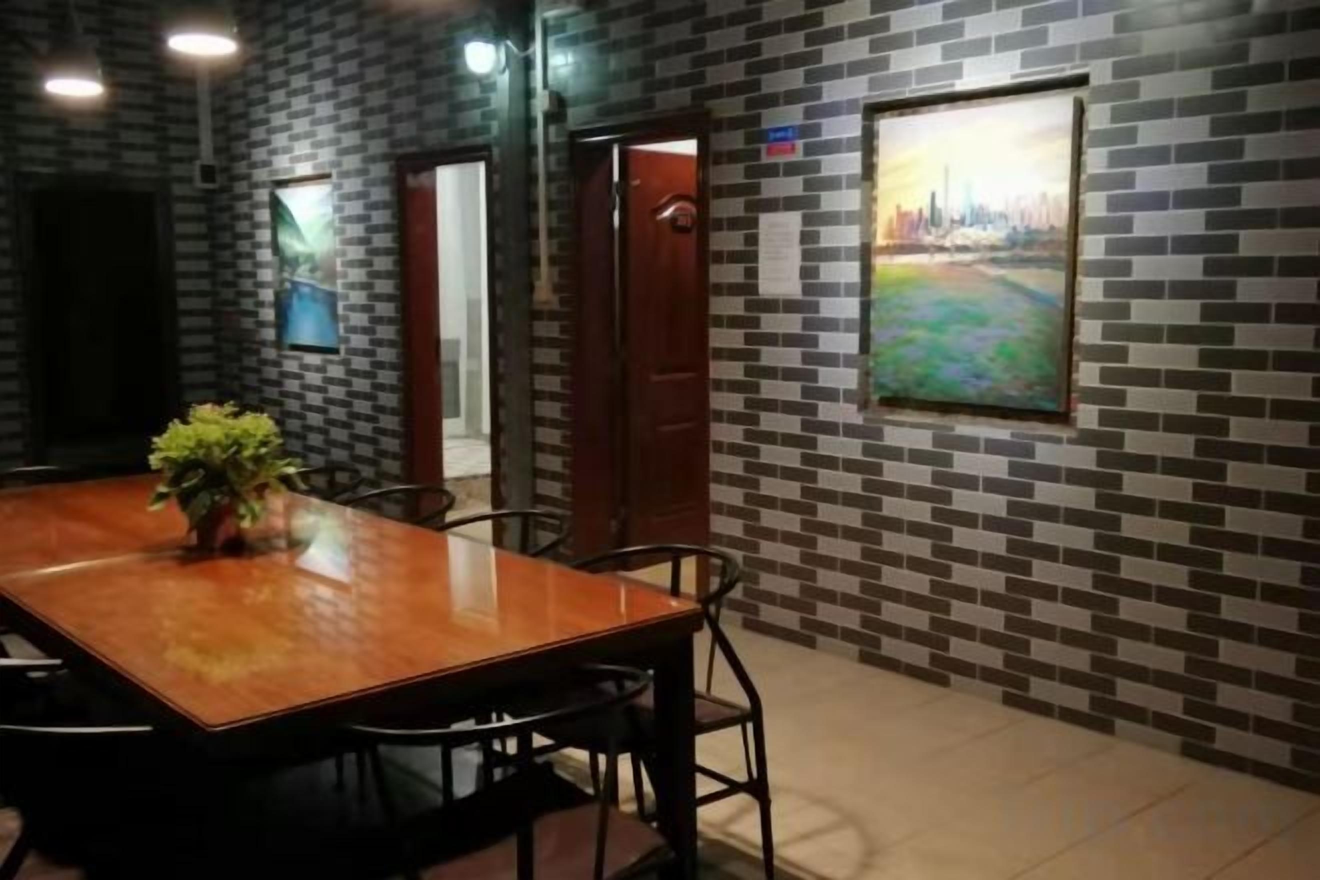A conference room with a wooden table and chairs, a potted plant, and a cityscape painting on the wall.