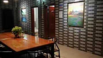 A conference room with a wooden table and chairs, a potted plant, and a cityscape painting on the wall.