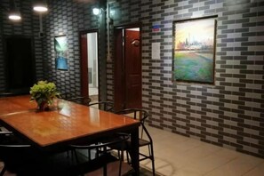 Une salle de conférence avec une table et des chaises en bois, une plante en pot et un tableau représentant un paysage urbain accroché au mur.
