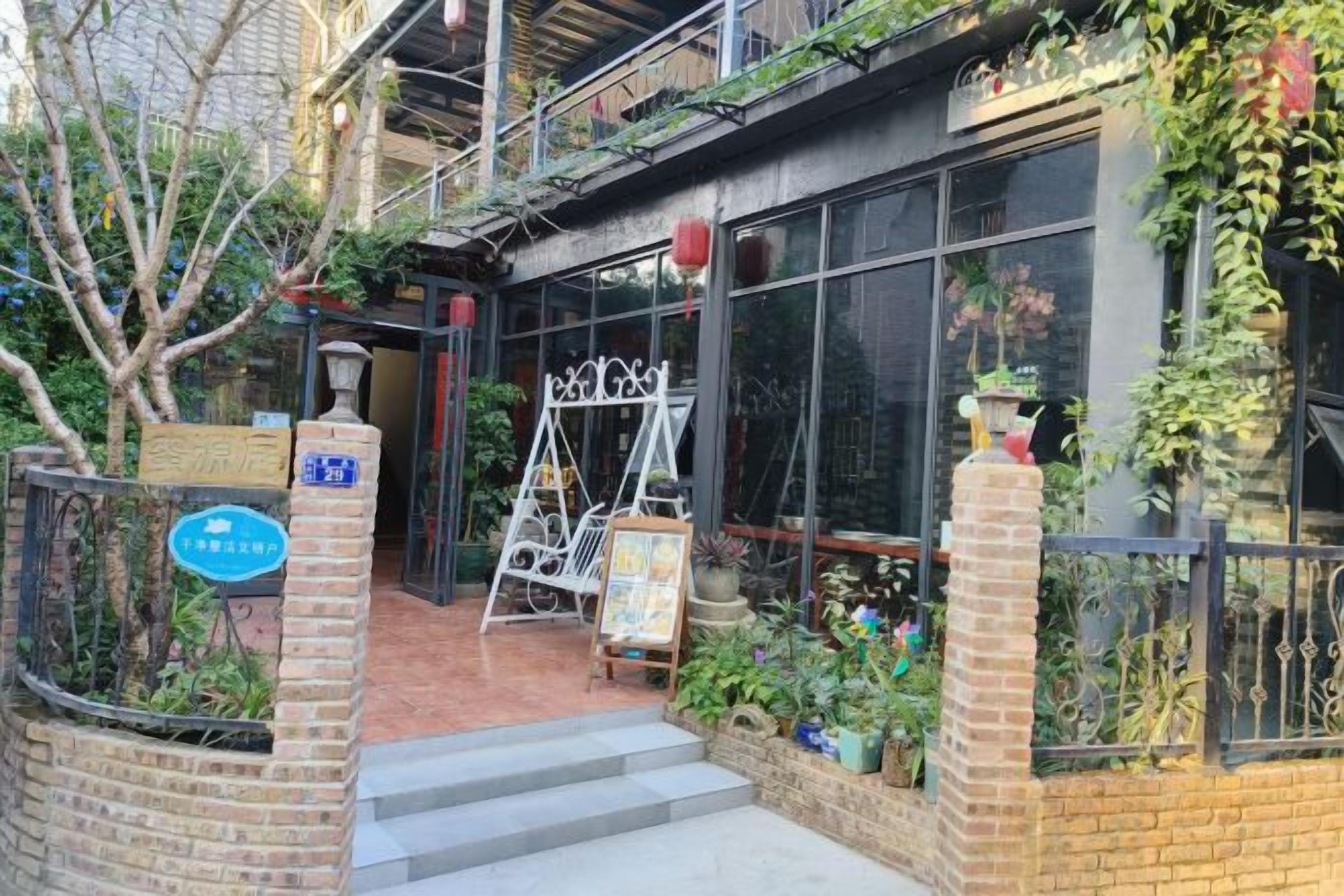 A building entrance with a brick facade, a metal gate, and a signboard.