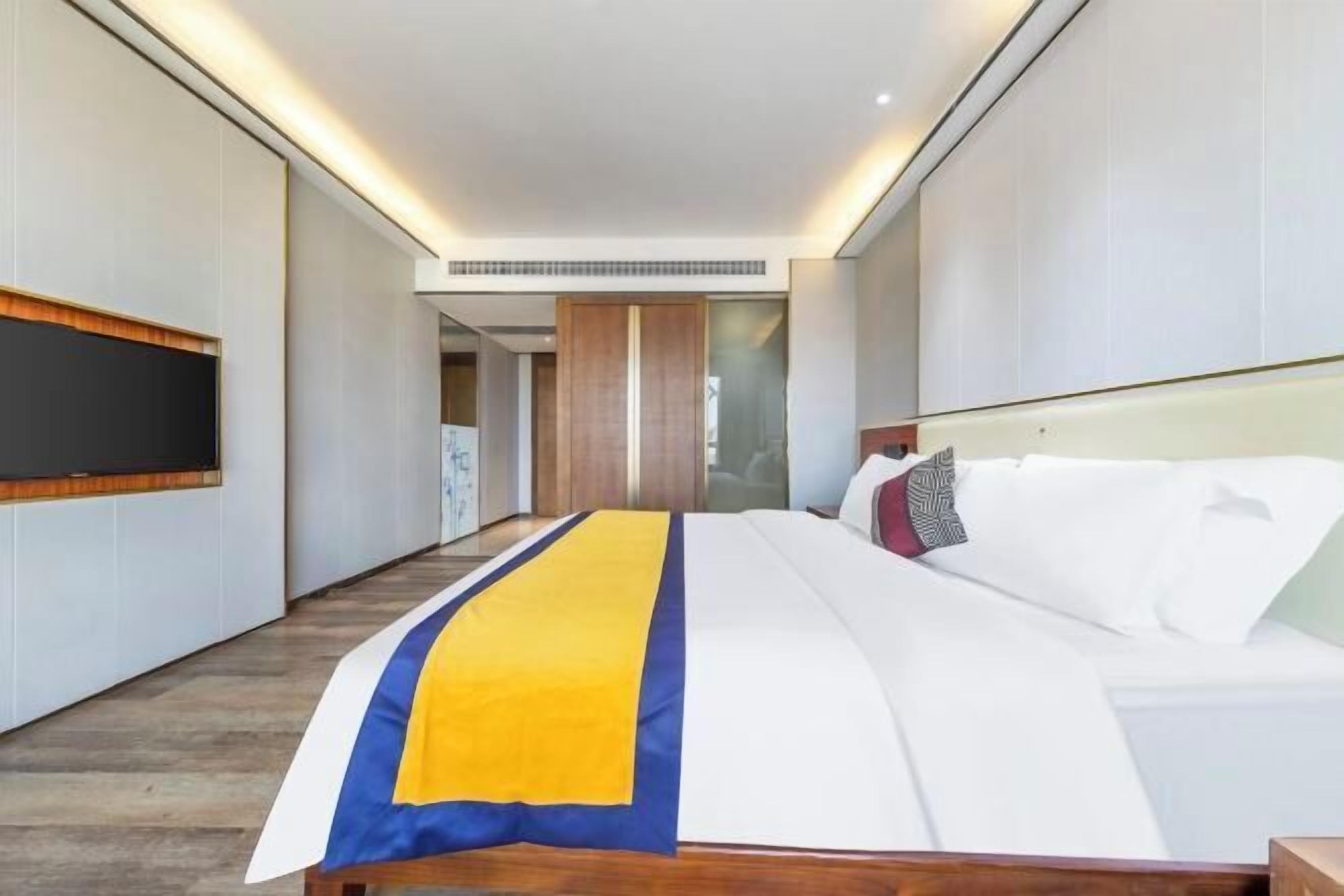 Habitación de hotel con cama, televisor y cabecero de madera.