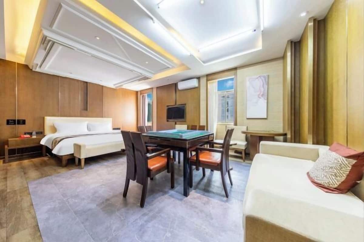 A hotel room with a bed, a dining table with chairs, a sofa, and a TV.