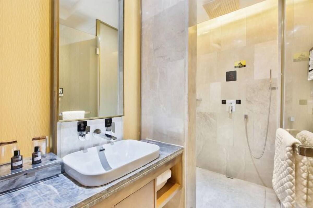 A modern bathroom with a marble sink, a glass-enclosed shower, and a large mirror.