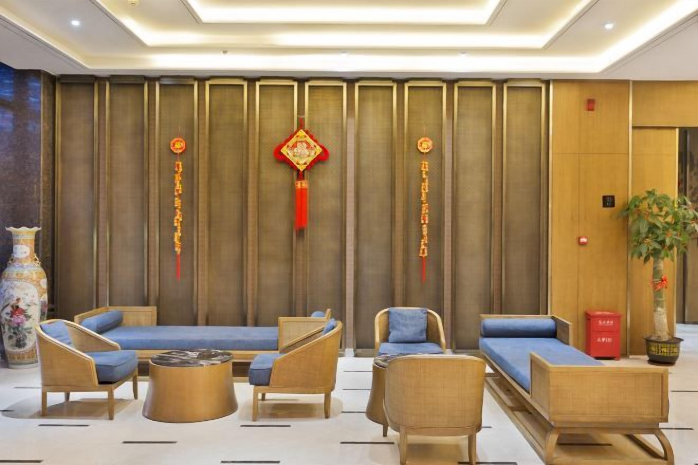 A hotel lobby with seating arrangements, a decorative wall, and a potted plant.