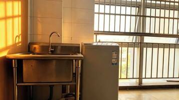 A kitchen with a sink, a refrigerator, and a window with bars.