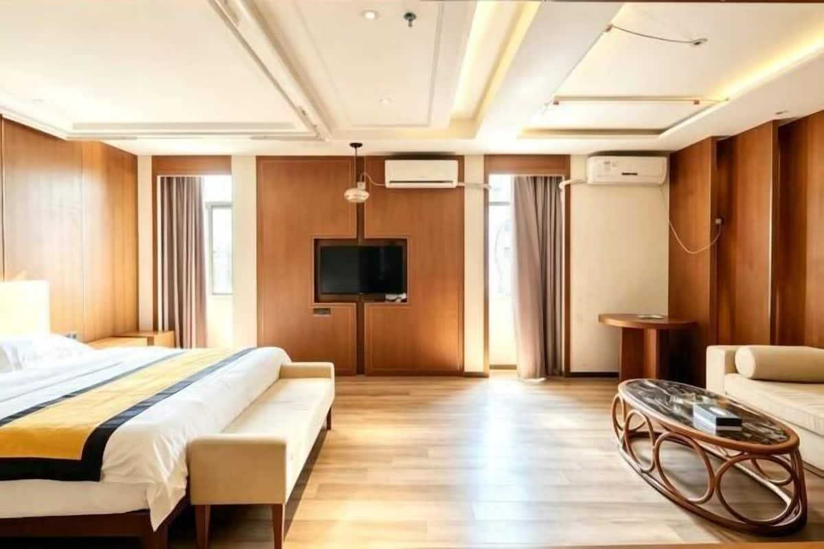 A hotel room with a bed, a sofa, a TV, and a small table.