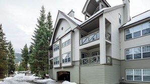 A multi-story building with a balcony, large windows, and a snow-covered ground. - Deer Run by Whistler Premier (Whistler)