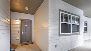 A house with a gray door marked "203", a window with white shutters, and a light fixture above the door. - Deer Run by Whistler Premier (Whistler)