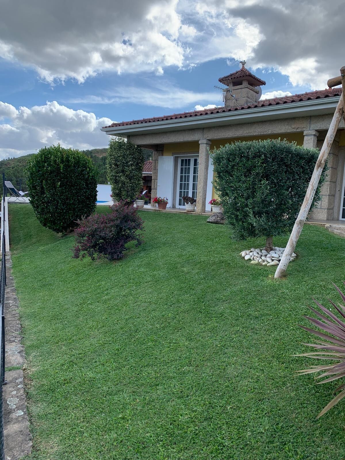 A house with a well-maintained lawn, a patio with potted plants, and a traditional architectural style.