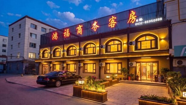 A hotel with a prominent sign, multiple windows, and a paved entrance area. - Hongfu Business Rooms (Panshi)