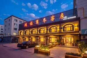 A hotel with a prominent sign, multiple windows, and a paved entrance area. - Hongfu Business Rooms (Panshi)