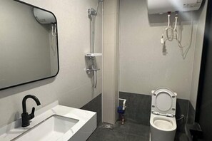 Une salle de bain moderne avec un lavabo blanc, un robinet noir, une douche et des toilettes.