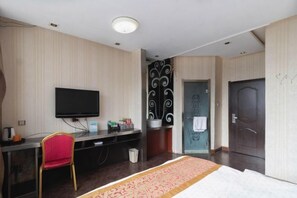 A hotel room with a bed, a desk with a chair, a television, a sink, and a door. - Hongfu Business Rooms (Panshi)