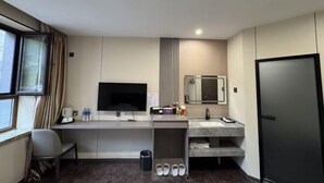 A modern hotel room with a desk, TV, sink, and refrigerator. - Hongfu Business Rooms (Panshi)