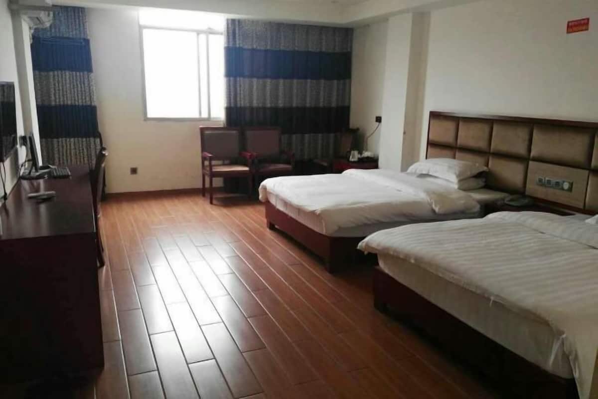 A hotel room with two beds, a desk, a chair, and a window with curtains.