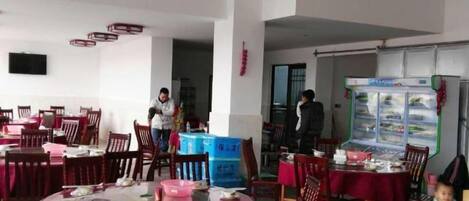 Un comedor con mesas redondas, sillas y una barra de servicio de alimentos.