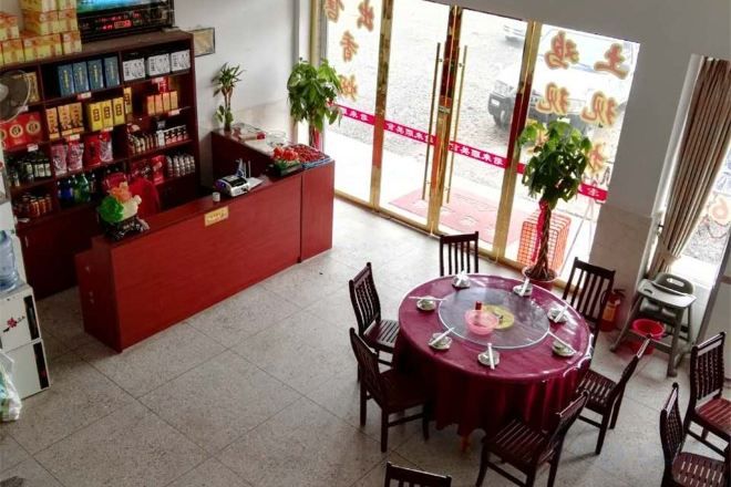A hotel lobby with a reception desk, a dining area with a round table, and a large window with a view.