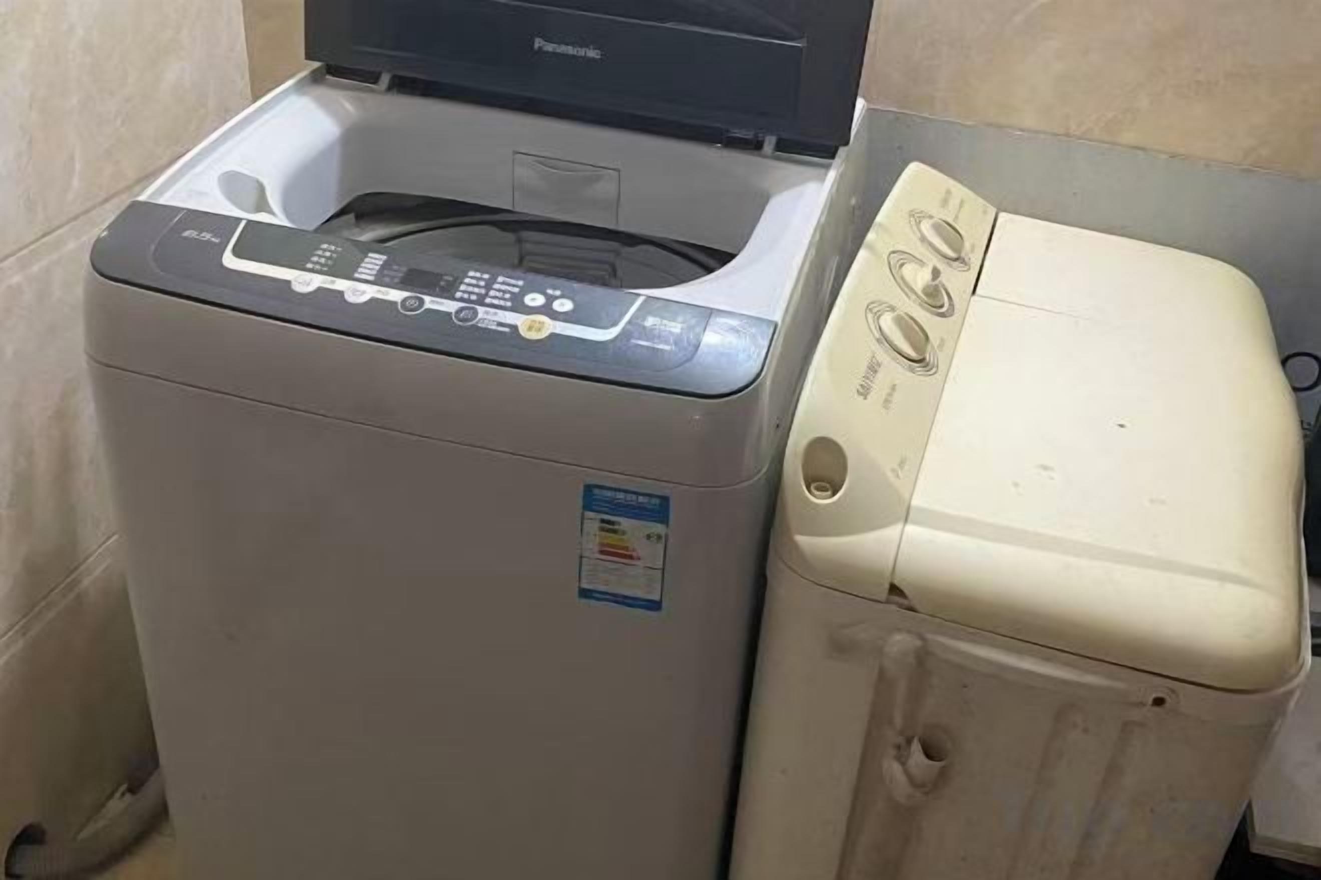Eine Waschmaschine mit Frontöffnung und ein Trockner stehen nebeneinander in einem Waschraum.