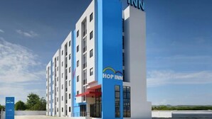 Un edificio de hotel de varios pisos, con el letrero "Hop Inn" bien visible.