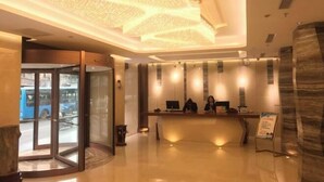 Vestíbulo de hotel con mostrador de recepción, una instalación de arte digital en el techo y puerta de entrada de cristal.