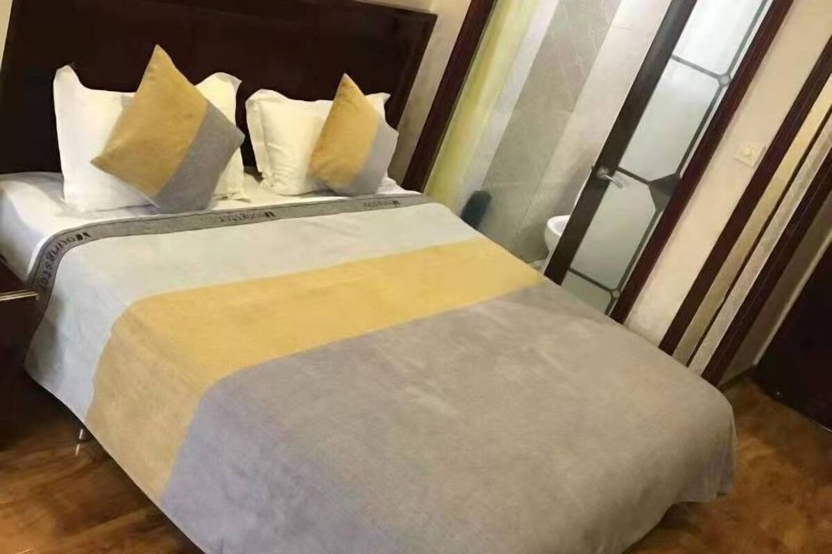 Habitación de hotel con cama, mesita de noche, espejo y ventana.