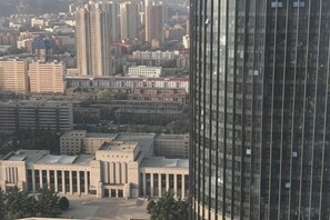 A high-rise building with a modern glass facade, surrounded by mid-rise buildings and a central plaza with a few trees. - Youhao Hotel (Lanzhou)