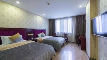 A hotel room with two beds, a desk, a chair, and a large window with curtains.